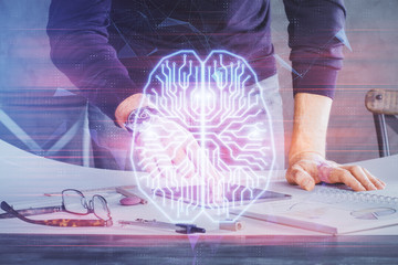 Double exposure of man's hand holding and using a digital device and brain hologram drawing. Data...