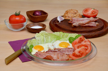 appetizer nutritious  breakfast bacon and fried eggs with vegetables on a wooden table
