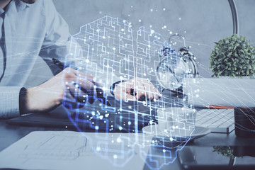 Double exposure of man's hand holding and using a digital device and brain hologram drawing. Data...