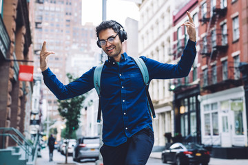 Ethnic young man in earphones dancing on street