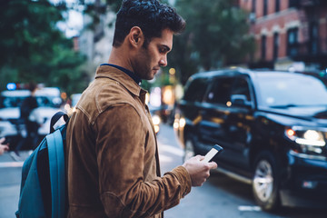Calm handsome man using smartphone in city