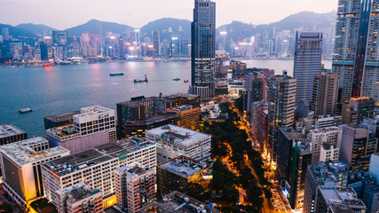 Aerial scenery panoramic view of Hong Kong Evening with metropolitan bay Victoria Harbor at sunset. Lighted Modern cityscape, urban skyline buildings. Energy power infrastructure. Popular Asian city
