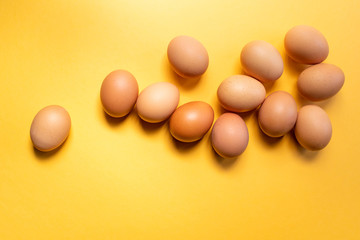 Group of fresh eggs on the table isolated on yellow background. Easter concept.