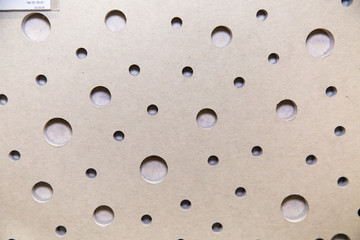 The background of the sound-absorbing plate is gray with a solid scattering perforation in the form of holes of different diameters, construction, texture, design.