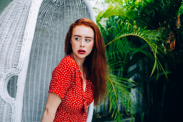 Alluring red haired woman sitting in wicker chair
