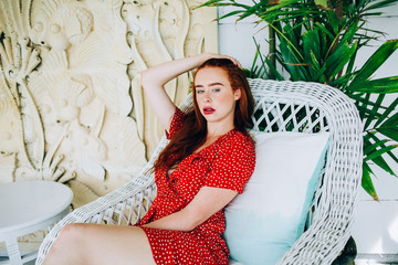 Alluring woman in dress on armchair in resort