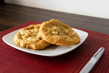 Tasty macadamia and white chocolate cookies on a plate