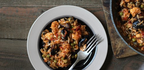 orzo pasta with mussels, seashells and chicken. Seafood paella, traditional spanish dish. Paella on rustic black wooden table. Top view
