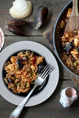 orzo pasta with mussels, seashells and chicken. Seafood paella, traditional spanish dish. Paella on rustic black wooden table. Top view