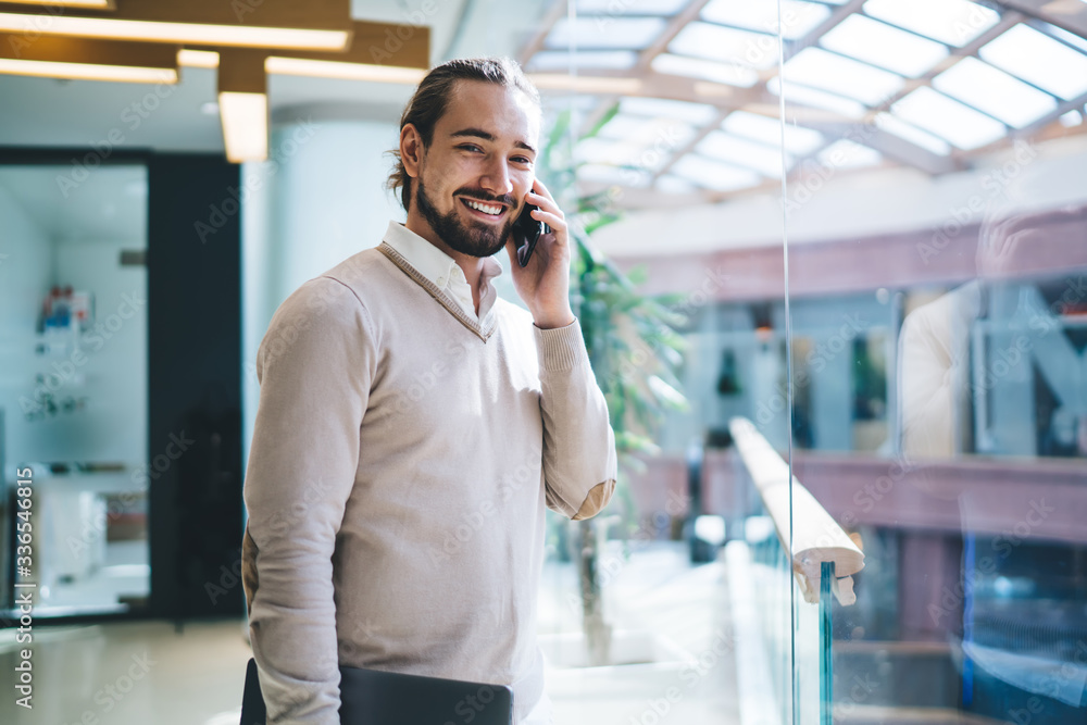 Poster half length portrait of cheerful employee using smartphone application for calling and talking about