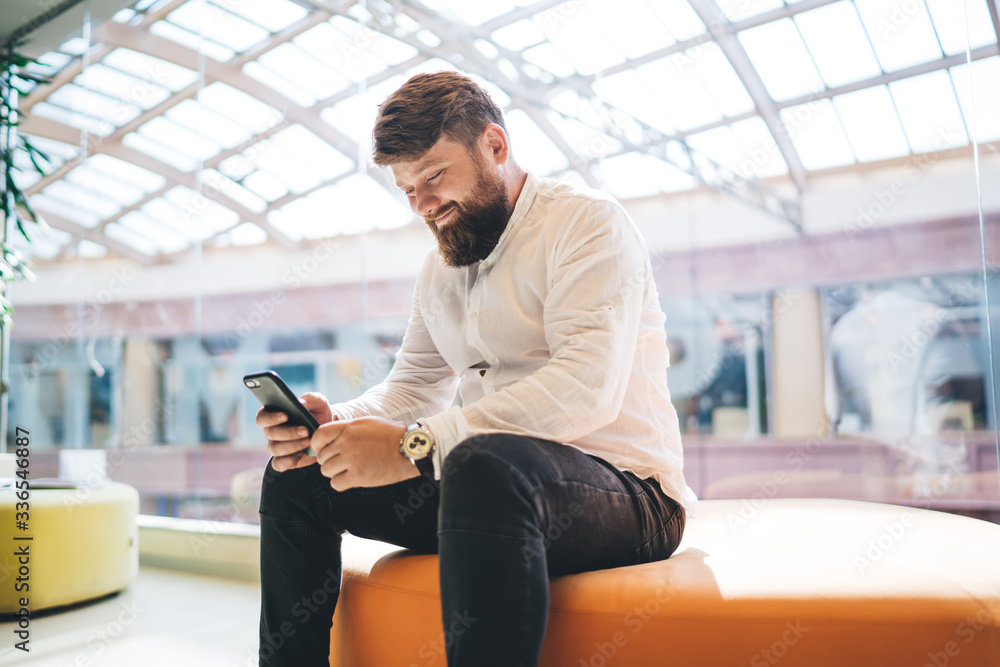 Poster cheerful man checking received email message on modern cellphone gadget using wireless internet conn