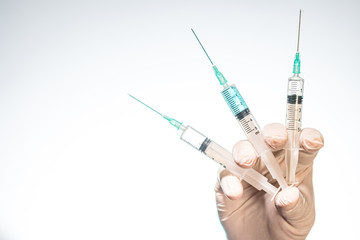 Hand wearing latex glove holding syringe with a medicine on white background