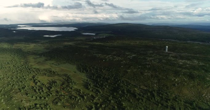 Spectacular aerial view of forest and lakes on flat pane of oyer. Drone fles towards meteorological tower.