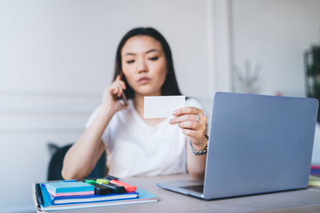 Smart female holding business card speaking on cellphone