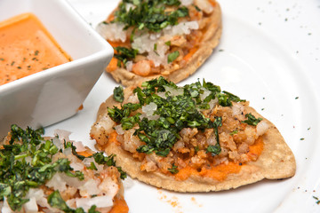 Chalupas con chicharrón de camarón, salsa picante, cilantro y cebolla, comida mexicana, plato blanco sobre fondo negro	