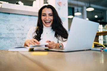 Portrait of cheerful female student 20s looking at camera during time for laptop e learning, happy...
