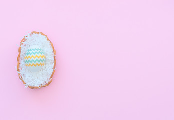 Decorated Easter egg lies in the basket on pink background. Happy Easter holiday concept. Greeting, invitation card. Flat lay style with copy space.