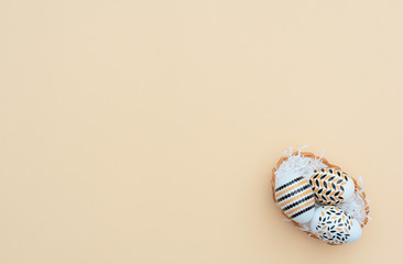 Decorated Easter eggs lie in the basket on yellow background. Happy Easter holiday concept. Greeting, invitation card. Flat lay style with copy space.