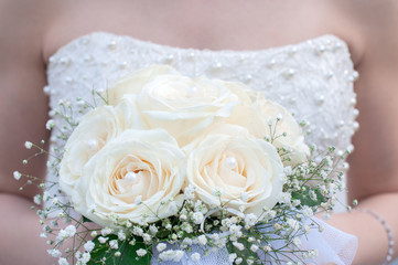 Bouquet of wedding roses on the hands of the bride
