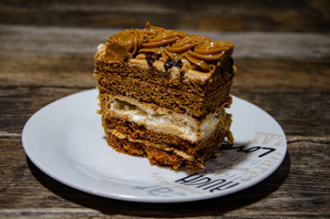 Slice of nut cake in a white plate on the kitchen wooden table.