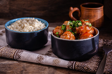 Cooking at home. Homemade meatballs and boiled rice in ceramic bowls, on a kitchen napkin. Fork and ceramic dishes.