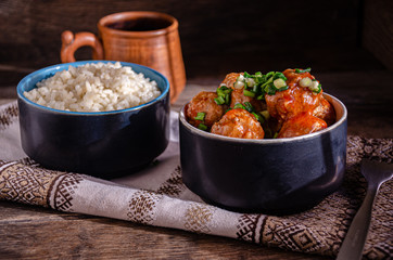 Cooking at home. Homemade meatballs and boiled rice in ceramic bowls, on a kitchen napkin. Fork and ceramic dishes.