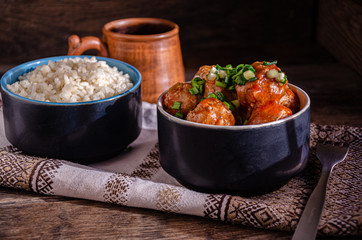 Cooking at home. Homemade meatballs and boiled rice in ceramic bowls, on a kitchen napkin. Fork and ceramic dishes.