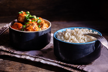 Cooking at home. Homemade meatballs and boiled rice in ceramic bowls, on a kitchen napkin. Fork and ceramic dishes.