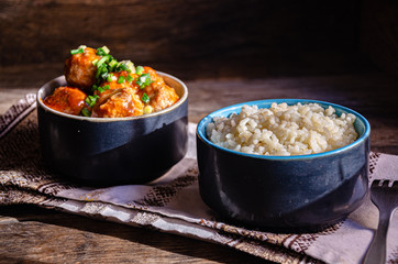 Cooking at home. Homemade meatballs and boiled rice in ceramic bowls, on a kitchen napkin. Fork and ceramic dishes.