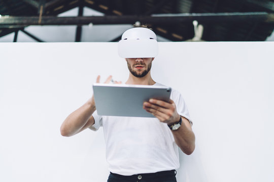 Serious man using tablet in virtual reality headset