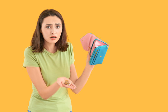 Worried young woman with empty wallet on color background