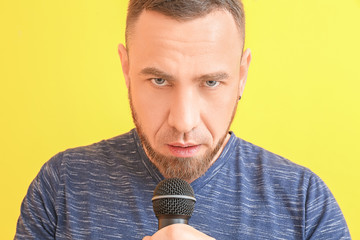 Male singer with microphone on color background