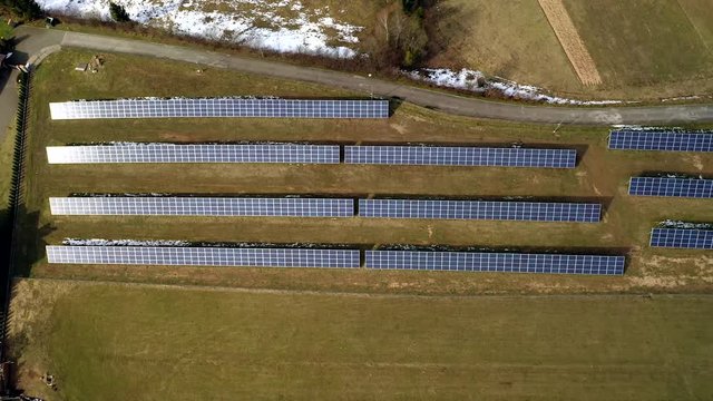 Aerial view of large field of solar photo voltaic panels system producing renewable clean energy on green grass background.