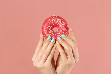 Foto op Canvas Hands of young woman with beautiful manicure and donut on color background © Pixel-Shot