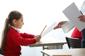 Schoolgirl giving teacher her answer sheet after passing exam