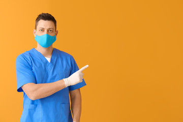 Doctor in protective medical mask pointing at something on color background