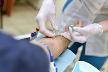  The process of taking venous blood through a needle for analysis in a patient of a male medical...