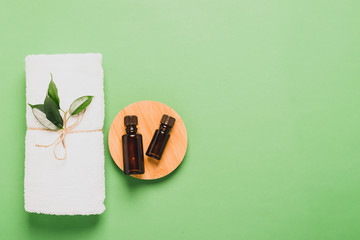 Aromatherapy bottle fresh tea tree leaf oil soft white towel for cosmetic spa treatments pastel green mint background .