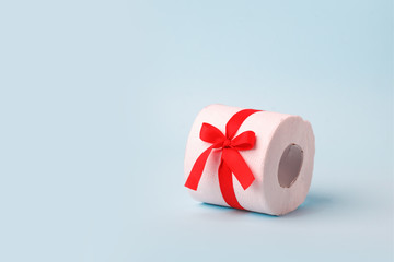 A roll of toilet paper wrapped in a gift bow. The concept of a valuable actual gift, a meme on the deficit in supermarkets, coronavirus covid-19, panic, excitement and shortage of goods, banner