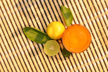 Top view of fresh lemon juice in glass and fresh yellow lemon put on bamboo table