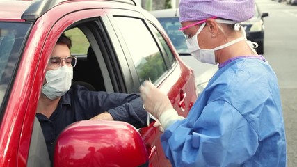 A doctor in a protective suit taking a nasal swab from a driver to test for possible coronavirus infection