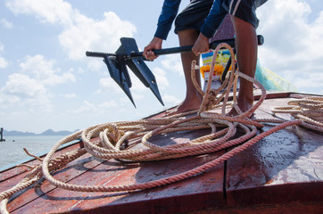 Working man on the boat with anchor and rope in hands © athapet