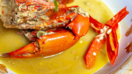 Indonesia crab curry garnished with red chili. Focus on the big claw