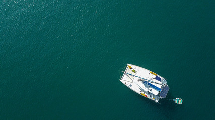 The drone captures a high angle view of catamaran sailboats moored in a tranquil bay.