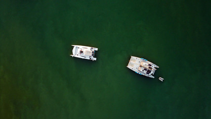 Fototapeta premium The drone captures a high angle view of catamaran sailboats moored in a tranquil bay.