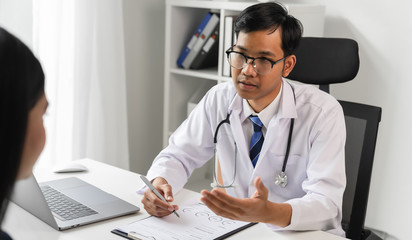 Asian doctor reports the symptoms and advises the patient.