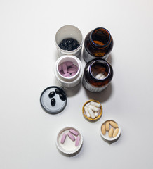 medicine pots with pills scattered on the table and inside the medicine lid.