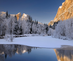 Three Brothers face and Cathedral Spires reflected in the Merced River after a snowfall in Yosemite