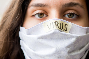 A close up of a teen girl with a mask and the word Virus on it. (The focus was placed on the word, not the eyes).