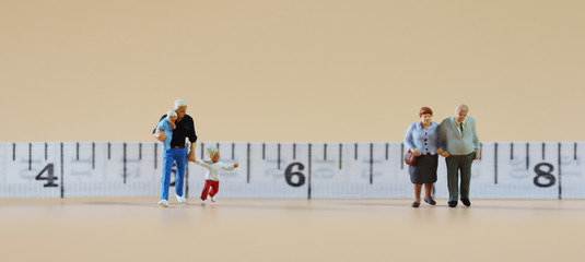 The miniature people standing in front of the tape measure. The concept of social distance.
